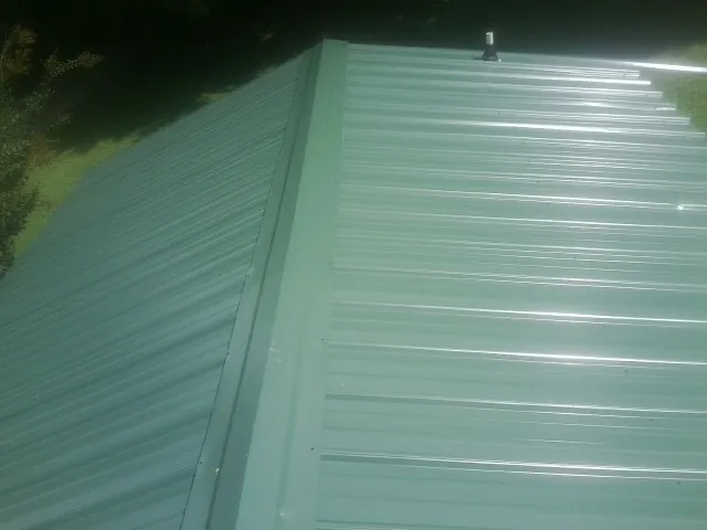 New green metal panels meeting at the ridge of a roof — Flat Roof Repair work by our crew in Maupin