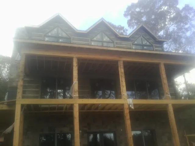 Dormers and porch framing on a large log home under construction — Roof Coating work by our crew in Maupin