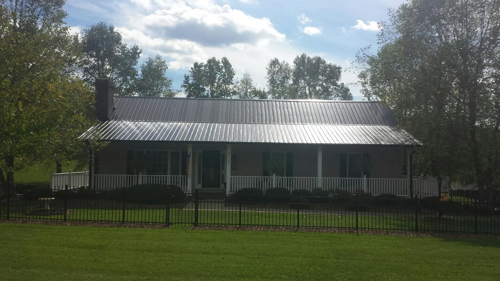 Gray metal roof on a brick ranch with a full width front porch — Gutter Guard Installation work by our crew in Maupin