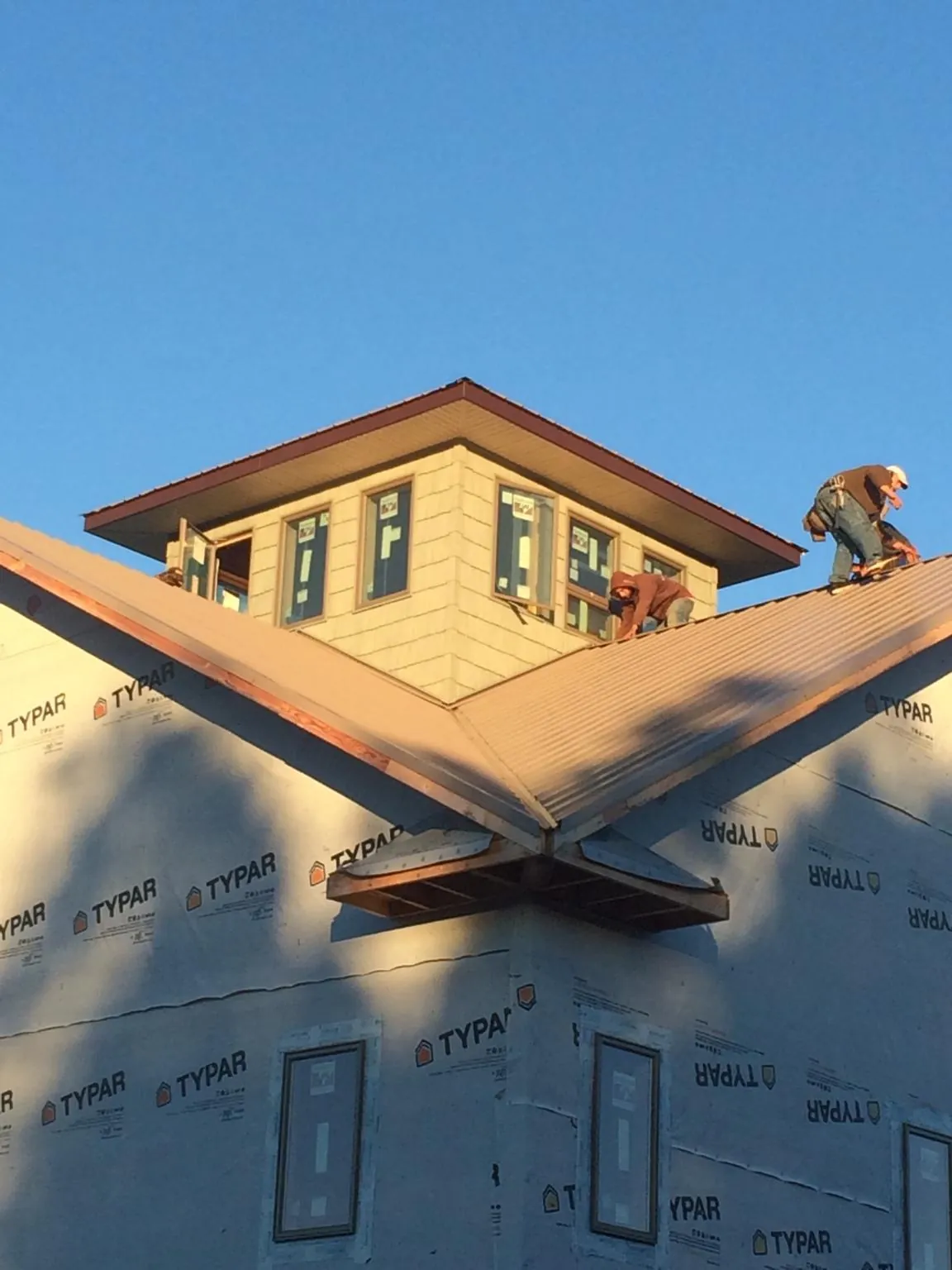 Roofers working around a rooftop cupola on a new metal roof at sunset — Roof Waterproofing in Maupin by Roofing Brothers